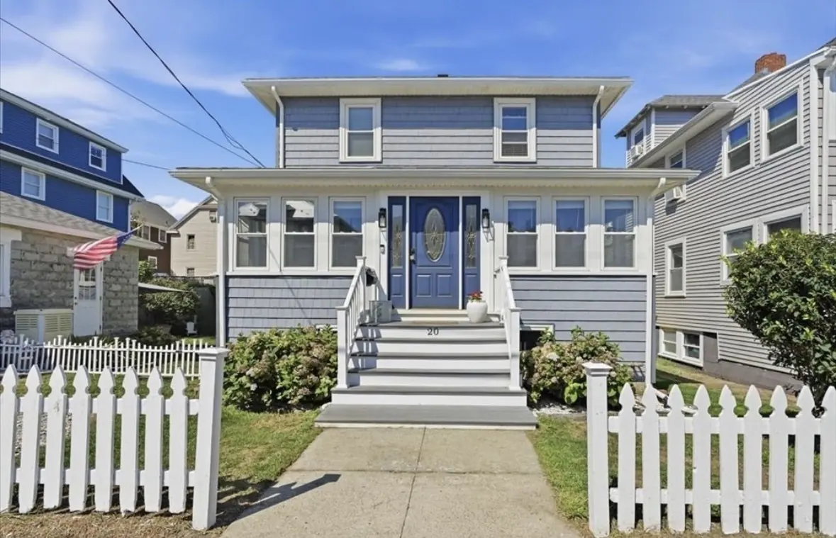 Front exterior of 20 Berkley Road, a coastal home with white picket fence and blue front door